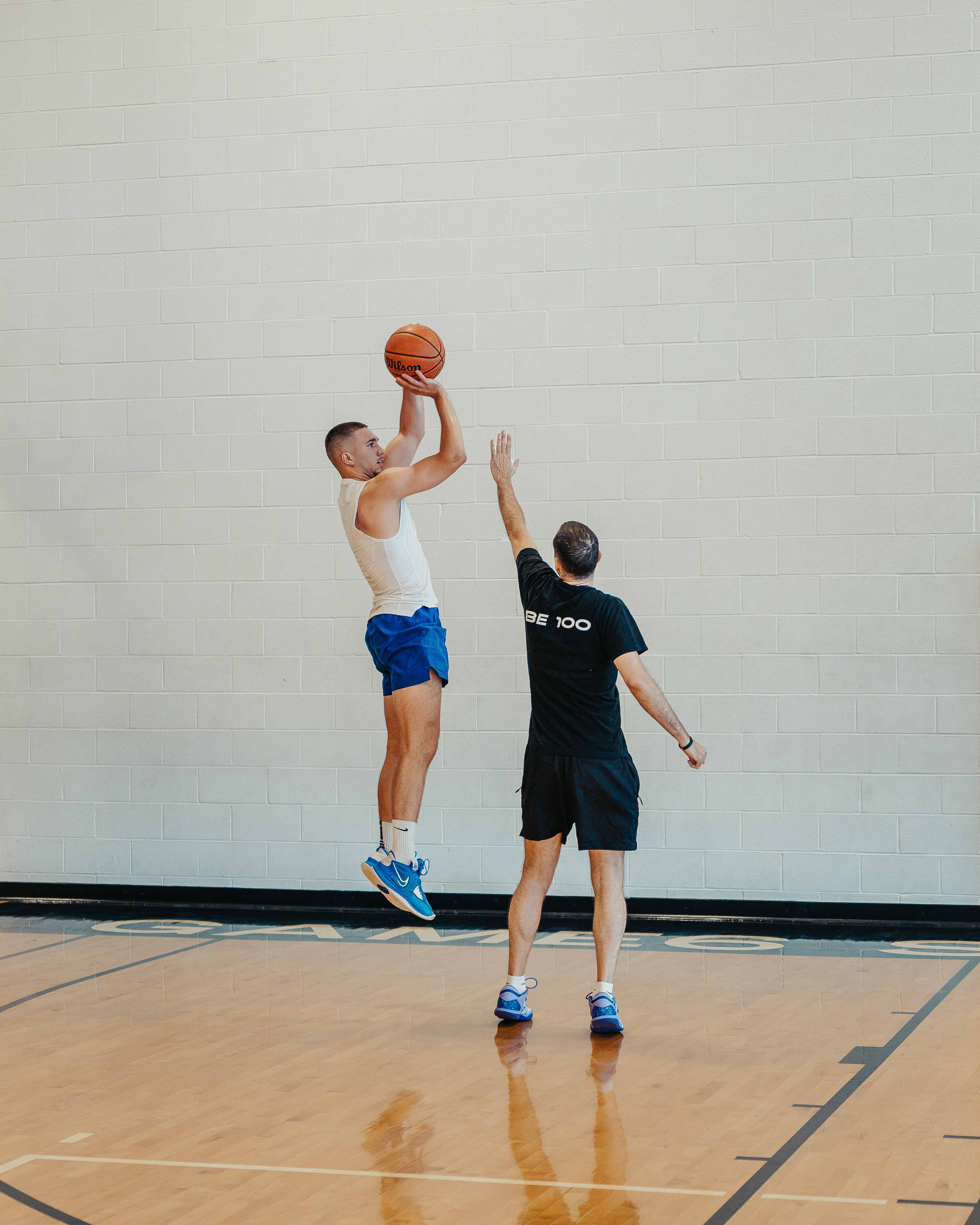 Player rising for a jump shot while the coach contests