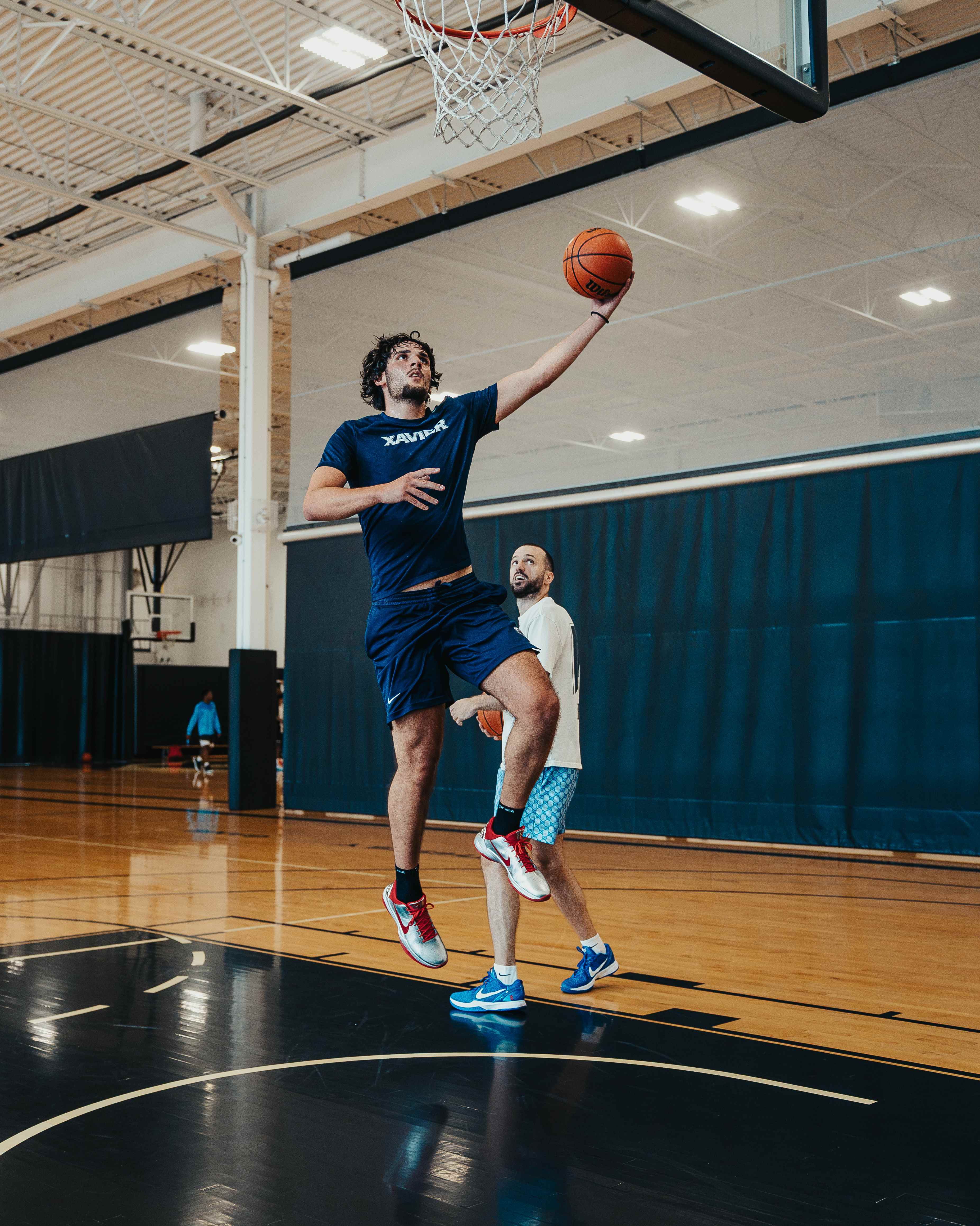 Player elevating for a layup as the coach looks on